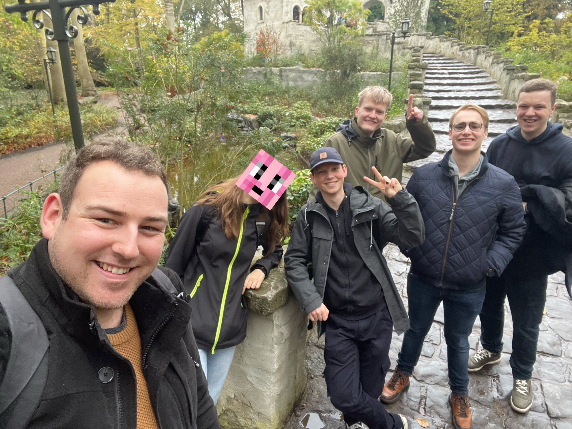 A Minecraft screenshot of Community Server 3's spawn town at sunset. Trees tower behind a row of waterfront buildings.